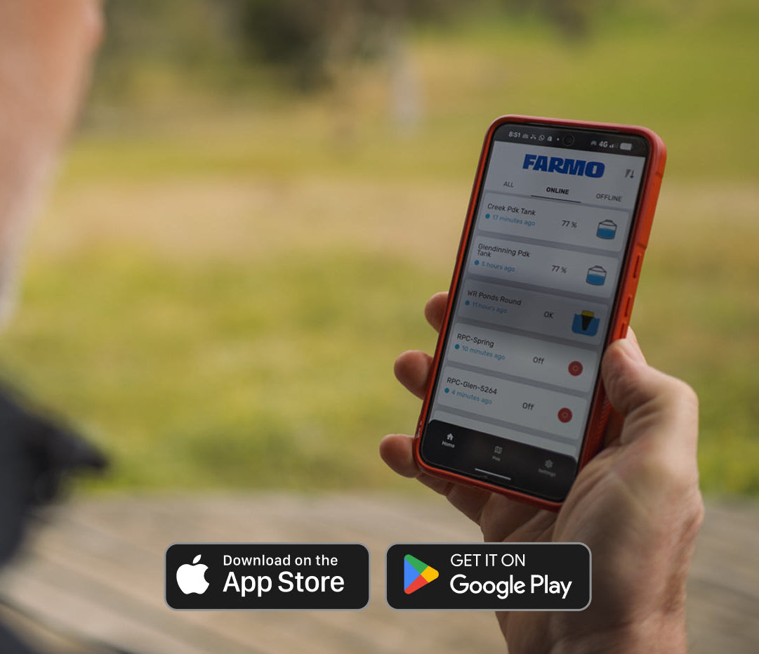 Person holding a smartphone with the Farmo app open, outdoors.